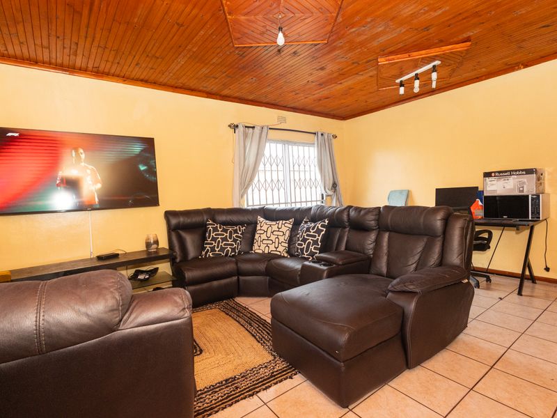 A living room featuring ceramic floor tiles and a timber tongue and groove ceiling, providing a functional space with potential for modern updates.
