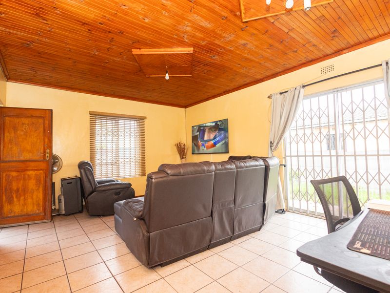 Living room featuring ceramic floor tiles, a timber tongue and groove ceiling, and a sliding glass door with security gate access to the exterior.
