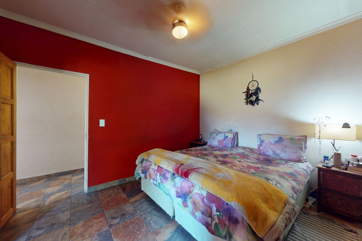 A bedroom featuring tiled flooring, a ceiling fan, and a solid wood door, with a bold red accent wall.