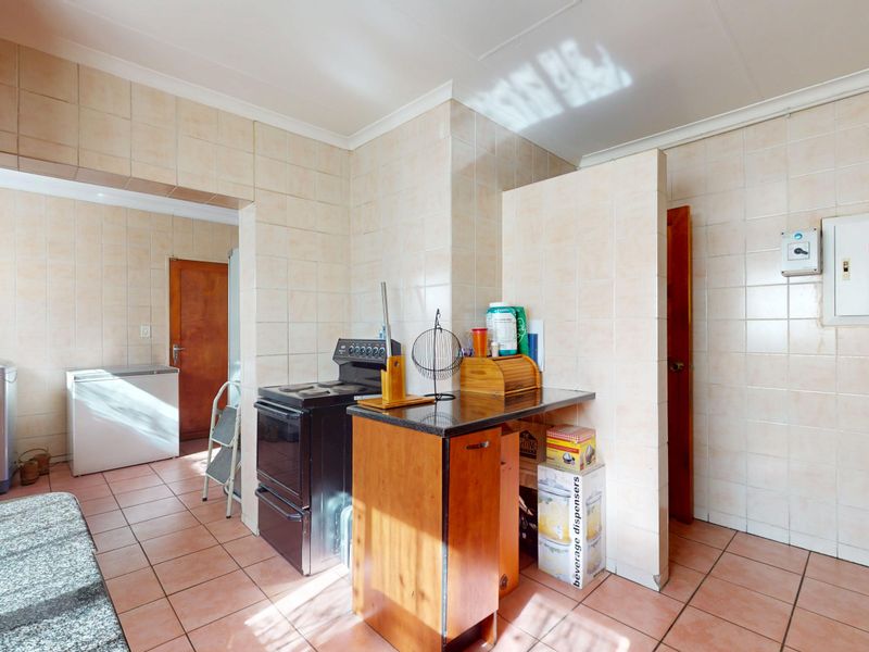A functional kitchen area featuring tiled walls and floors, a freestanding stove, and built-in cabinetry, offering potential for modernization and layout optimization.
