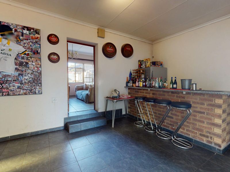 A dedicated bar area featuring a built-in brick counter with a stone top and tiled flooring, providing a functional space for entertaining.