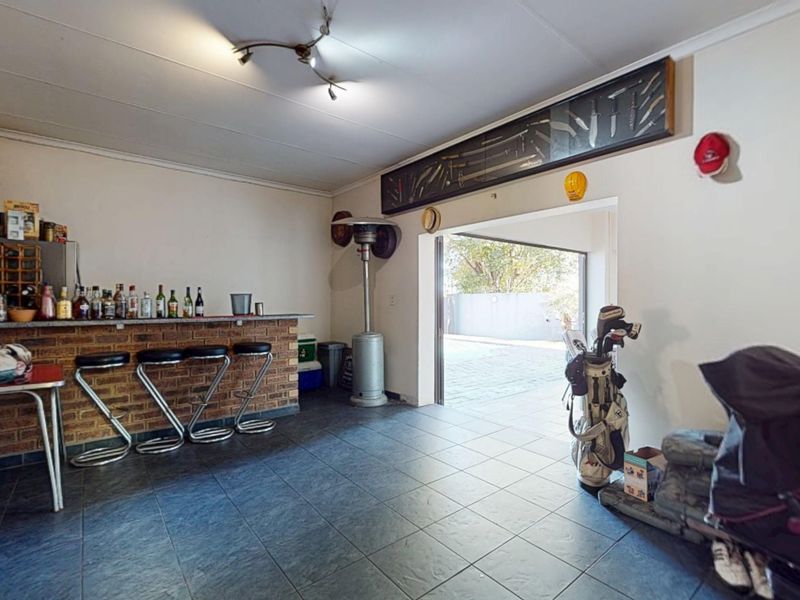 A dedicated bar area featuring a built-in brick counter, tiled flooring, and direct access to an outdoor patio space.