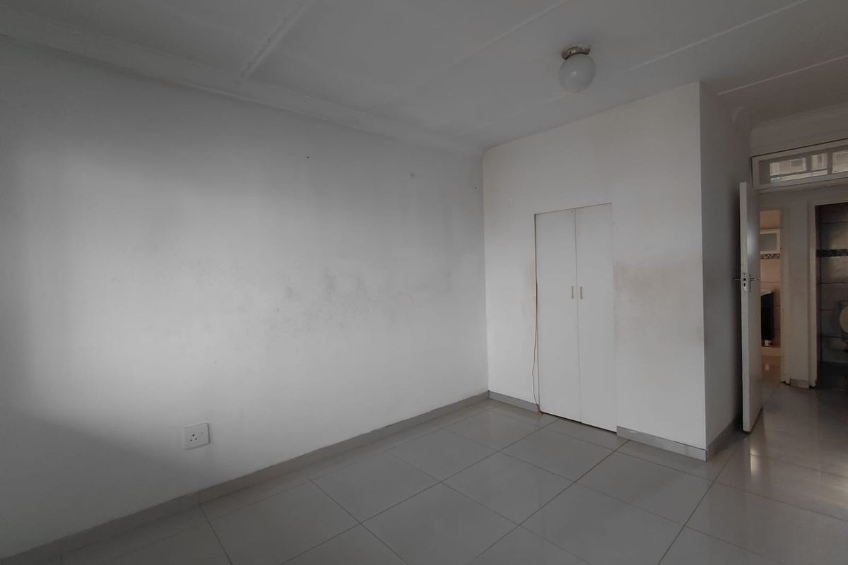 An empty bedroom featuring tiled flooring and a built-in cupboard, requiring minor cosmetic attention to the walls.