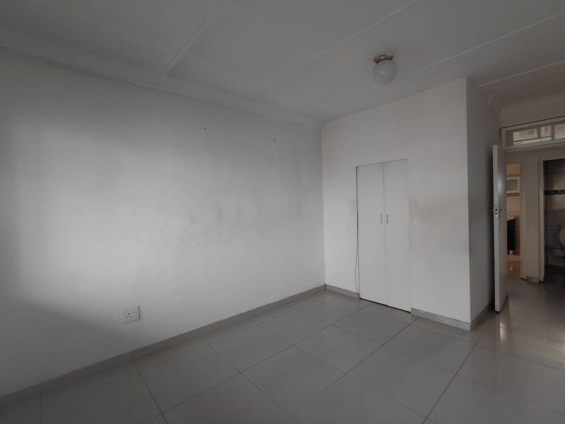 An empty bedroom featuring tiled flooring and a built-in cupboard, requiring minor cosmetic attention to the walls.