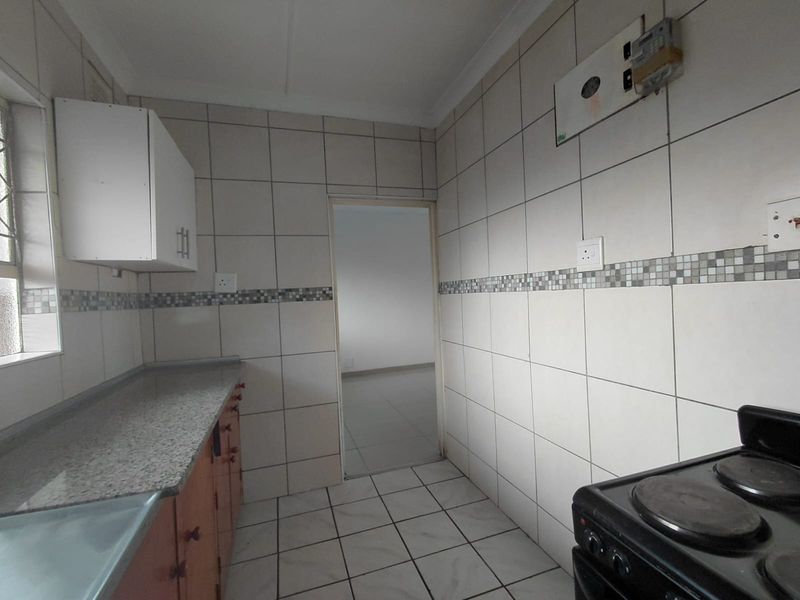 A functional kitchen featuring tiled walls, granite countertops, and built-in cabinetry, providing a clean and practical space for culinary activities.