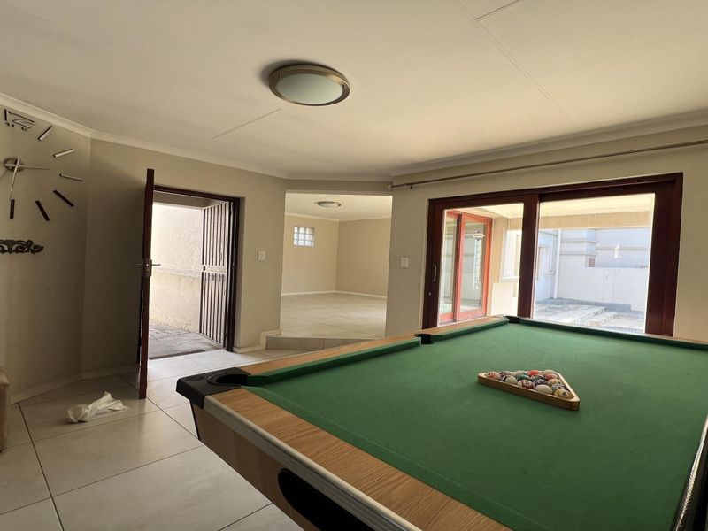 Spacious living area featuring tiled flooring, coved ceilings, and large sliding glass doors providing access to the outdoor patio area.