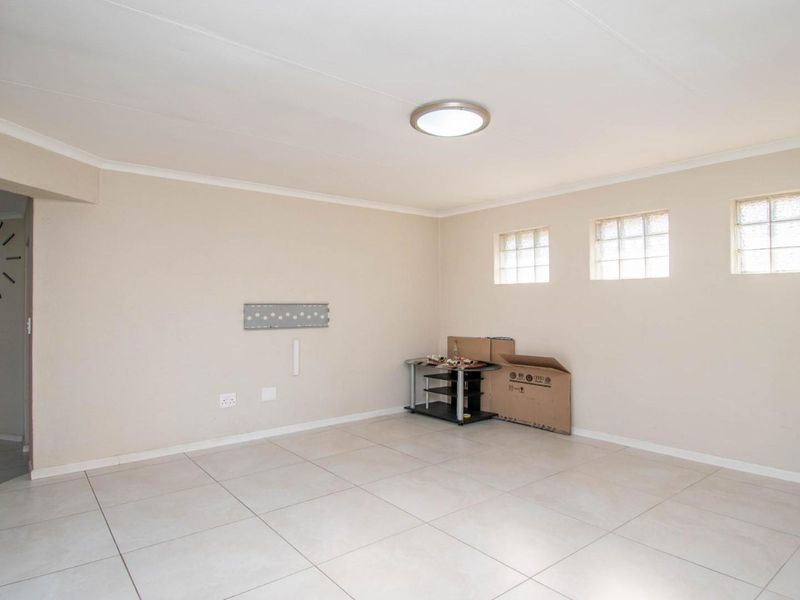 A spacious, neutral living area featuring tiled flooring, glass block windows, and a clean, open layout ready for personalization.