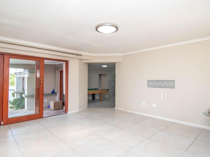 Spacious living area featuring neutral tiled flooring, a large sliding glass door providing outdoor access, and clean, well-maintained wall finishes.