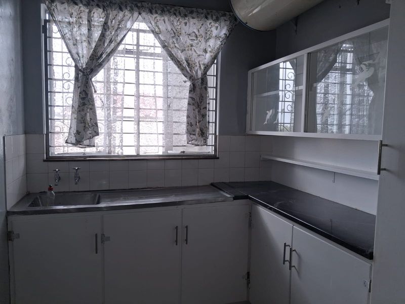 A functional kitchen space featuring built-in cabinetry, a stainless steel sink, and dark laminate countertops, ready for a modern update.