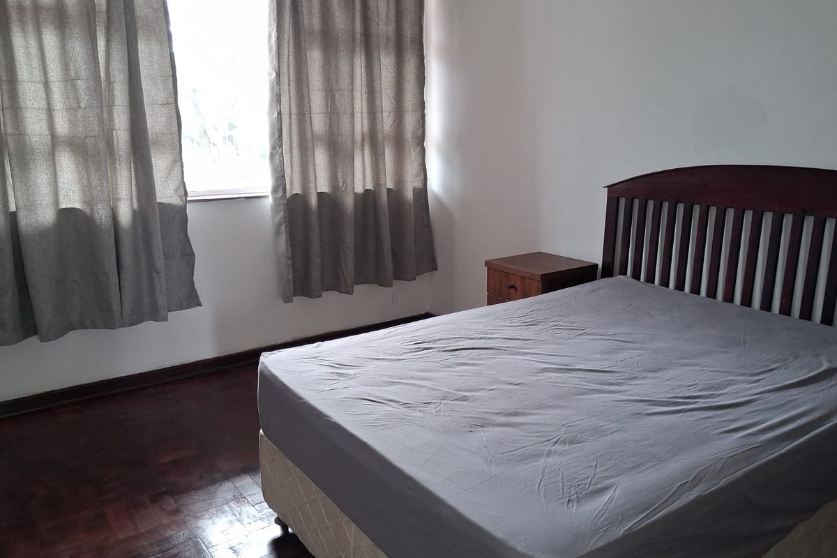 A bedroom featuring dark parquet flooring and a window with natural light, providing a neutral foundation for interior design updates.