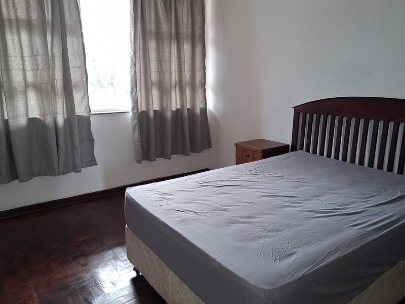 A bedroom featuring dark parquet flooring and a window with natural light, providing a neutral foundation for interior design updates.