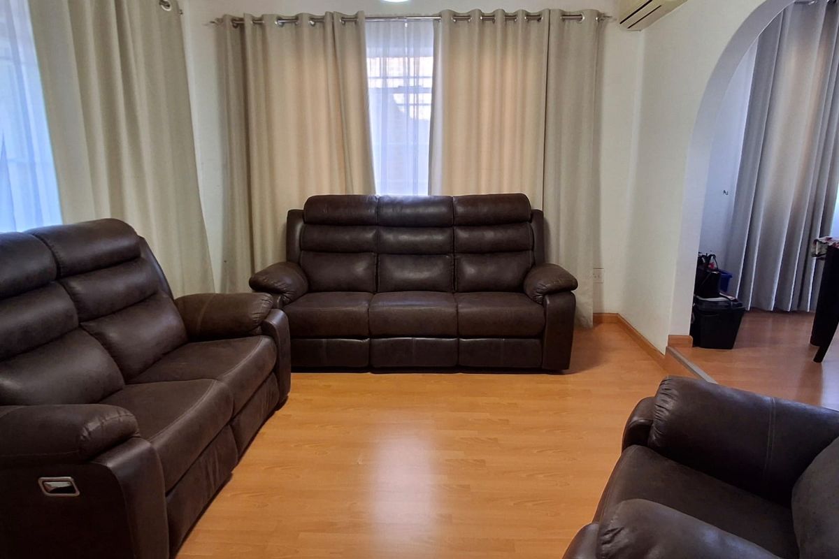 A living room featuring a timber ceiling, laminate flooring, and a split-system air conditioner, connected to an adjacent space via an archway.