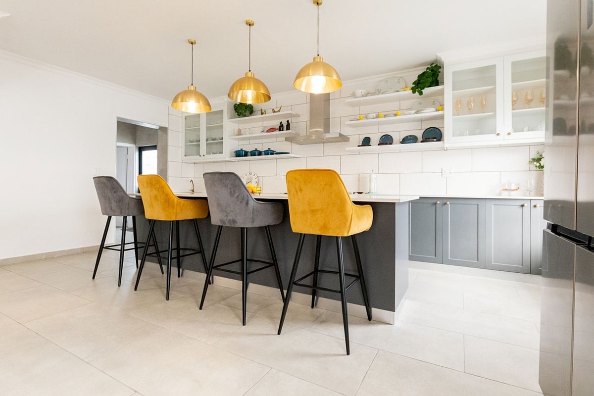 Modern kitchen featuring a central island with breakfast bar seating, shaker-style cabinetry, subway tile backsplash, and elegant gold pendant lighting.