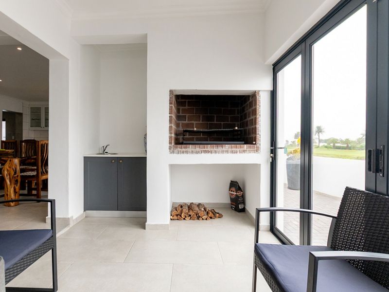 Covered patio area featuring a built-in brick braai, integrated cabinetry with a sink, and large sliding glass doors leading to the exterior.