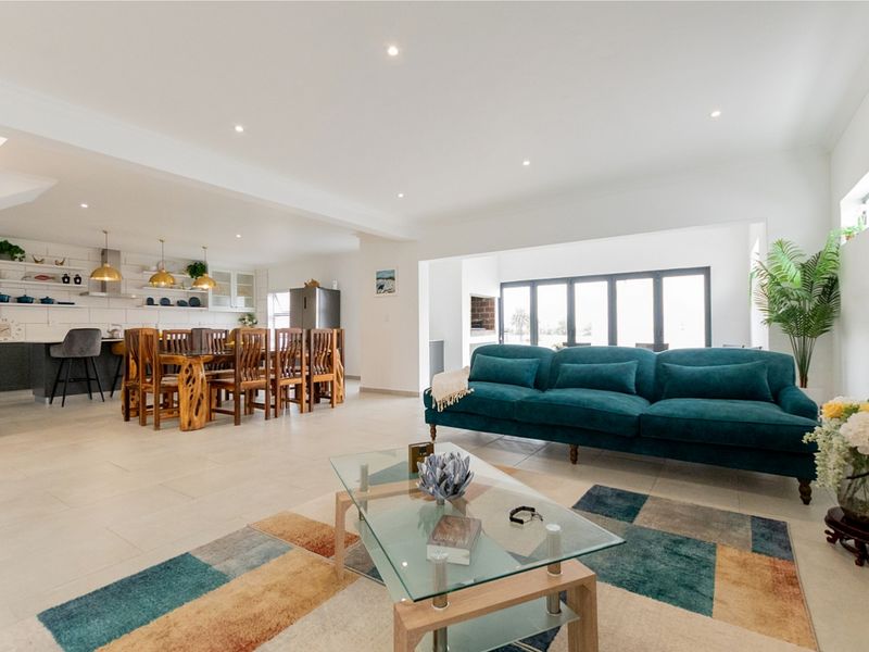 Spacious open-plan living and dining area featuring modern tiled floors, recessed lighting, and a well-appointed kitchen with integrated appliances and bi-fold doors.