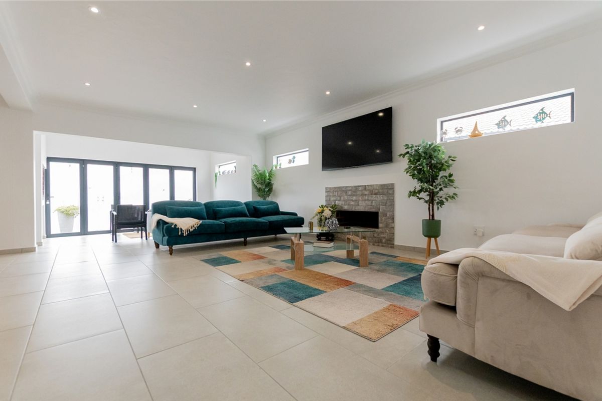 Spacious living room featuring a stone-clad fireplace, modern tiled flooring, recessed lighting, and large bi-fold doors providing seamless access to the outdoor area.