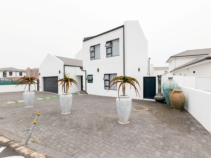 Modern double-storey residential property featuring a paved driveway, double garage, and clean white facade with contemporary architectural lines.