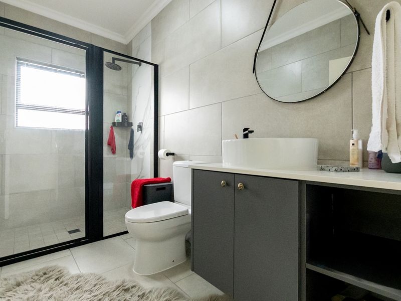 Modern bathroom featuring a walk-in shower with black-framed glass, a contemporary vanity with a vessel sink, and neutral large-format wall tiling.