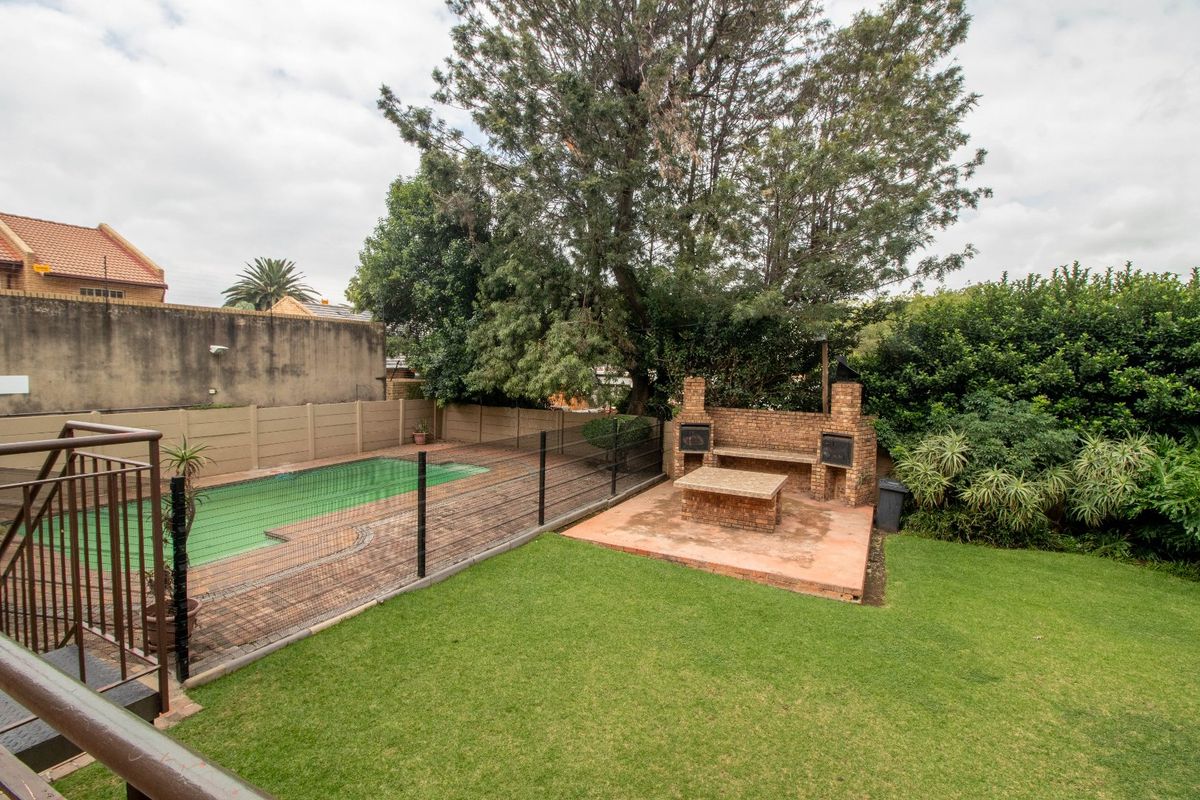Rear garden featuring a swimming pool with safety fencing, a paved patio area, and a brick built-in braai facility.