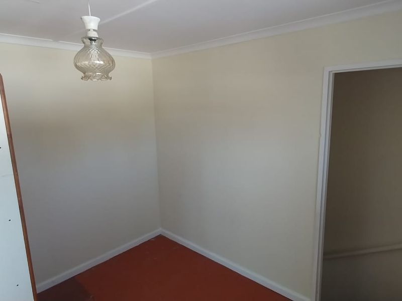 A vacant bedroom featuring neutral walls, coving, and a pendant light fitting, offering a blank canvas for renovation or restyling.