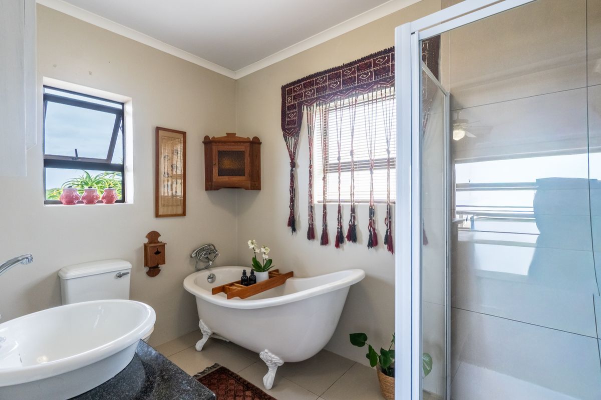 A well-maintained bathroom featuring a classic clawfoot bathtub, a separate glass-enclosed shower, and a vanity basin with modern fixtures.