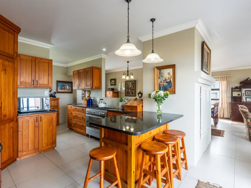 Open plan kitchen featuring warm wooden cabinetry, granite countertops, a gas stove, and a breakfast bar, seamlessly flowing into the adjacent living area.