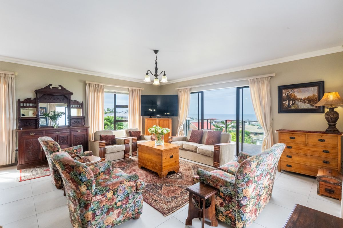 Spacious living room featuring tiled flooring, large sliding glass doors with ocean views, and classic crown molding details.