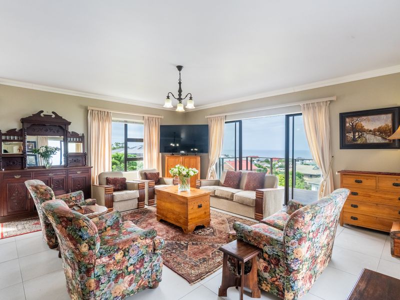 Spacious living room featuring tiled flooring, large sliding glass doors with ocean views, and classic crown molding details.
