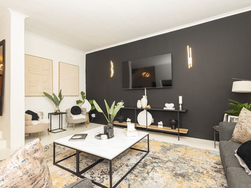 A modern living room featuring a striking black accent wall, exposed brick detailing, and contemporary wall-mounted lighting fixtures.