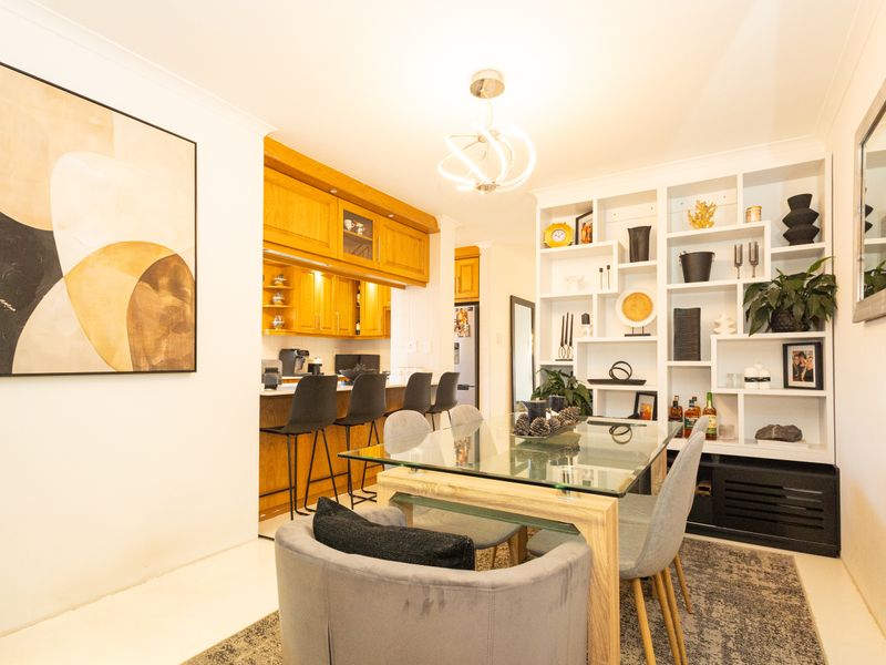 Open plan dining area featuring a breakfast bar with wooden cabinetry and a large built-in white shelving unit.