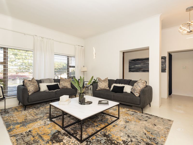A bright and spacious living room featuring polished concrete floors, modern lighting, and large windows that allow for ample natural light.