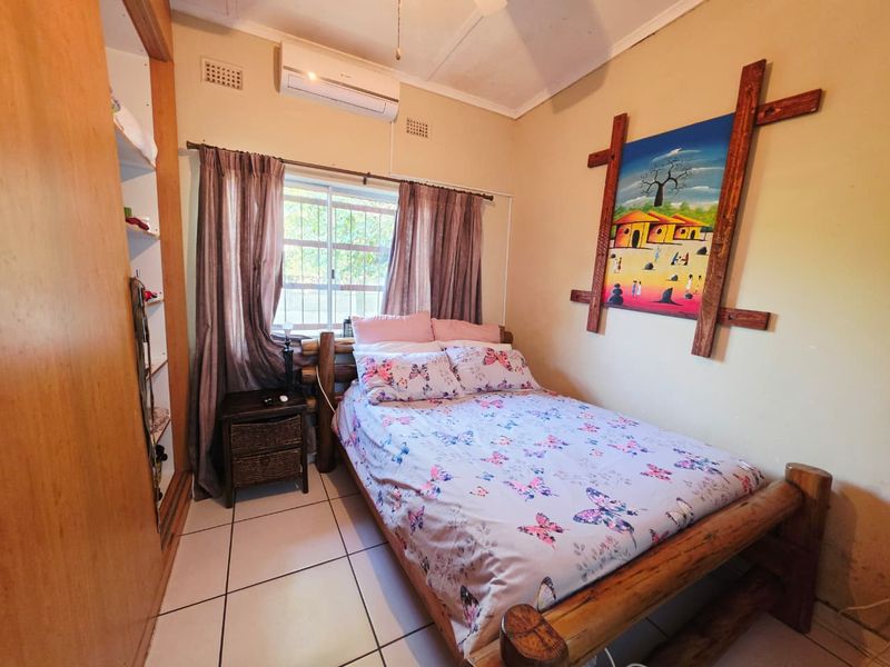 A functional bedroom featuring tiled flooring, a built-in wardrobe, and a wall-mounted air conditioning unit.