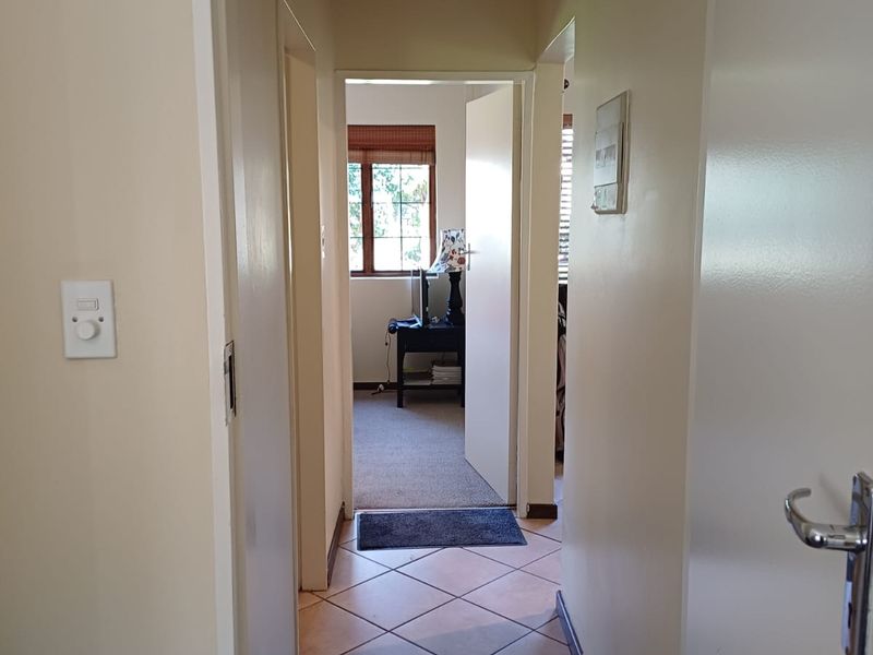 A functional hallway with tiled flooring connecting to adjacent rooms, featuring neutral wall finishes and standard internal door frames.