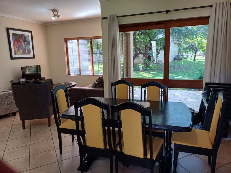 Open plan dining and living area featuring tiled flooring and large sliding glass doors providing direct access to the garden.