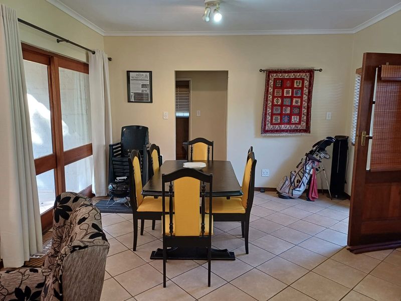 A dining room featuring tiled flooring, a sliding glass door providing natural light, and access to an adjacent hallway.