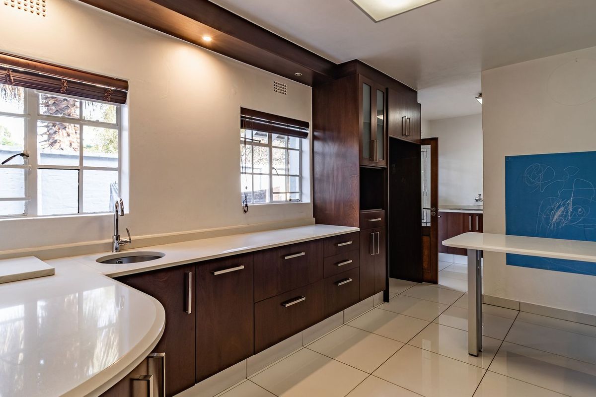 Modern kitchen featuring dark wood cabinetry, stone countertops, tiled flooring, and a built-in breakfast bar with ample natural light.