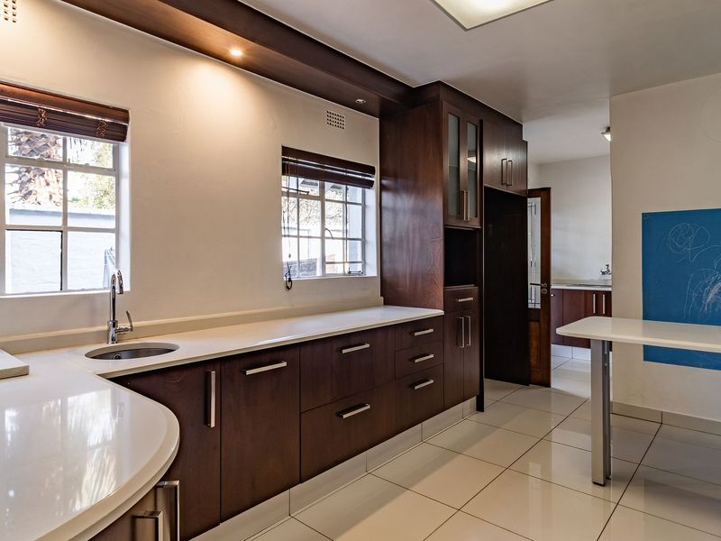Modern kitchen featuring dark wood cabinetry, stone countertops, tiled flooring, and a built-in breakfast bar with ample natural light.