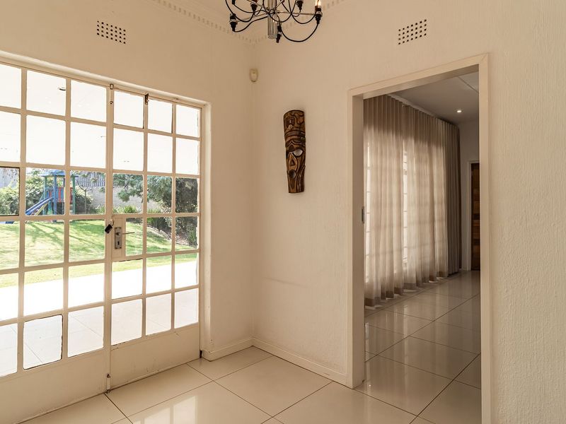 Bright entrance hall featuring tiled flooring, classic coving, and a large glass-paned door providing direct access to the garden.