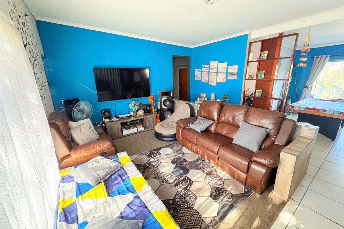 A living room featuring a combination of tiled and carpeted flooring, bright blue walls, and a ceiling fan.