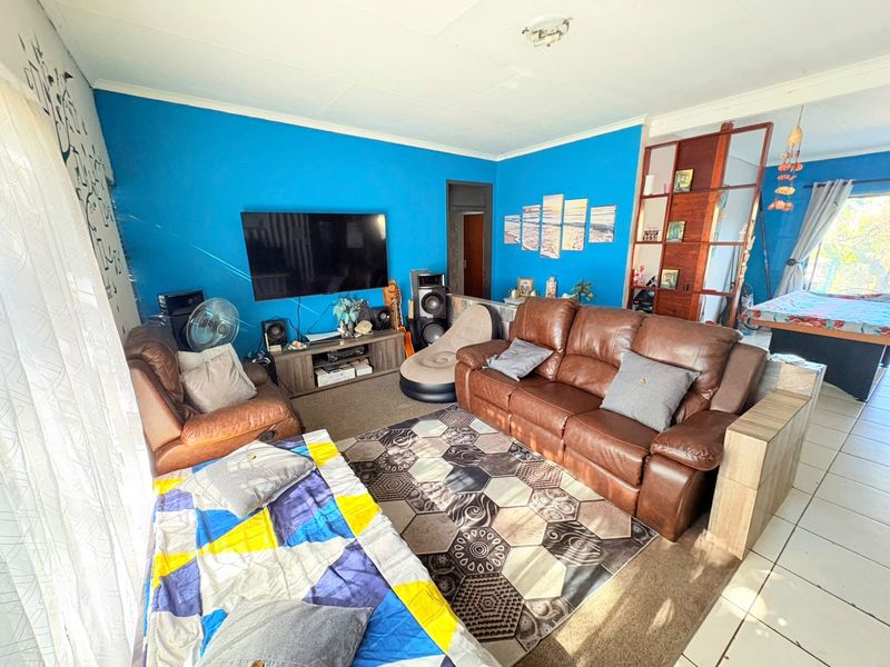 A living room featuring a combination of tiled and carpeted flooring, bright blue walls, and a ceiling fan.
