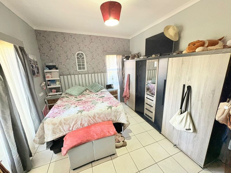A bedroom featuring tiled flooring, a built-in wardrobe, and a feature wallpaper wall.