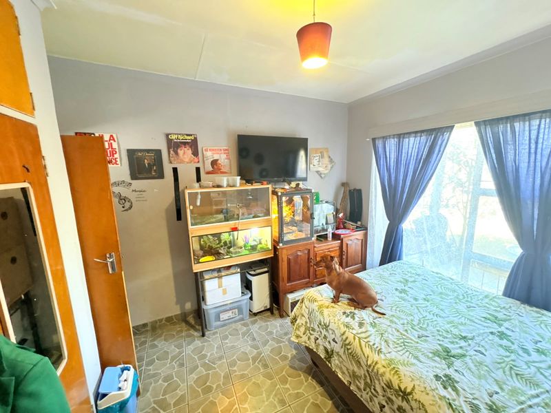 A bedroom featuring tiled flooring, a built-in cupboard, and a sliding glass door providing natural light.