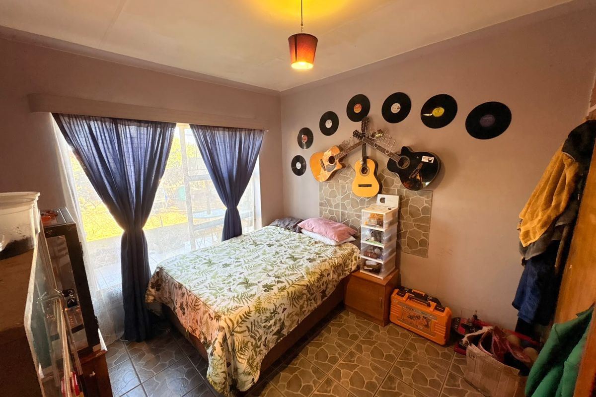 A bedroom featuring tiled flooring, a central pendant light fixture, and a large window providing natural light.