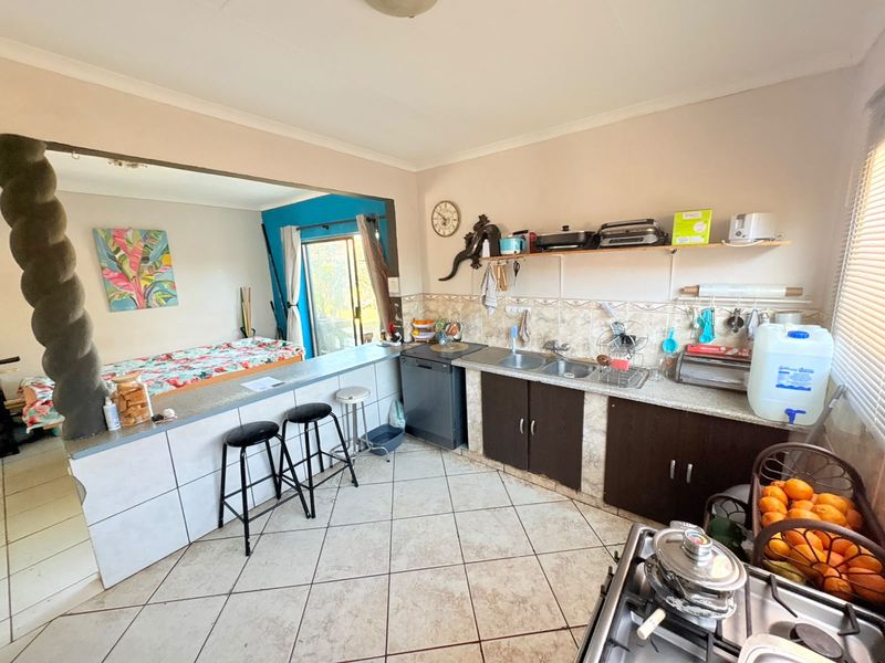Open-plan kitchen and living area featuring a breakfast bar, double sink, gas stove, and tiled flooring with direct access to an outdoor space.