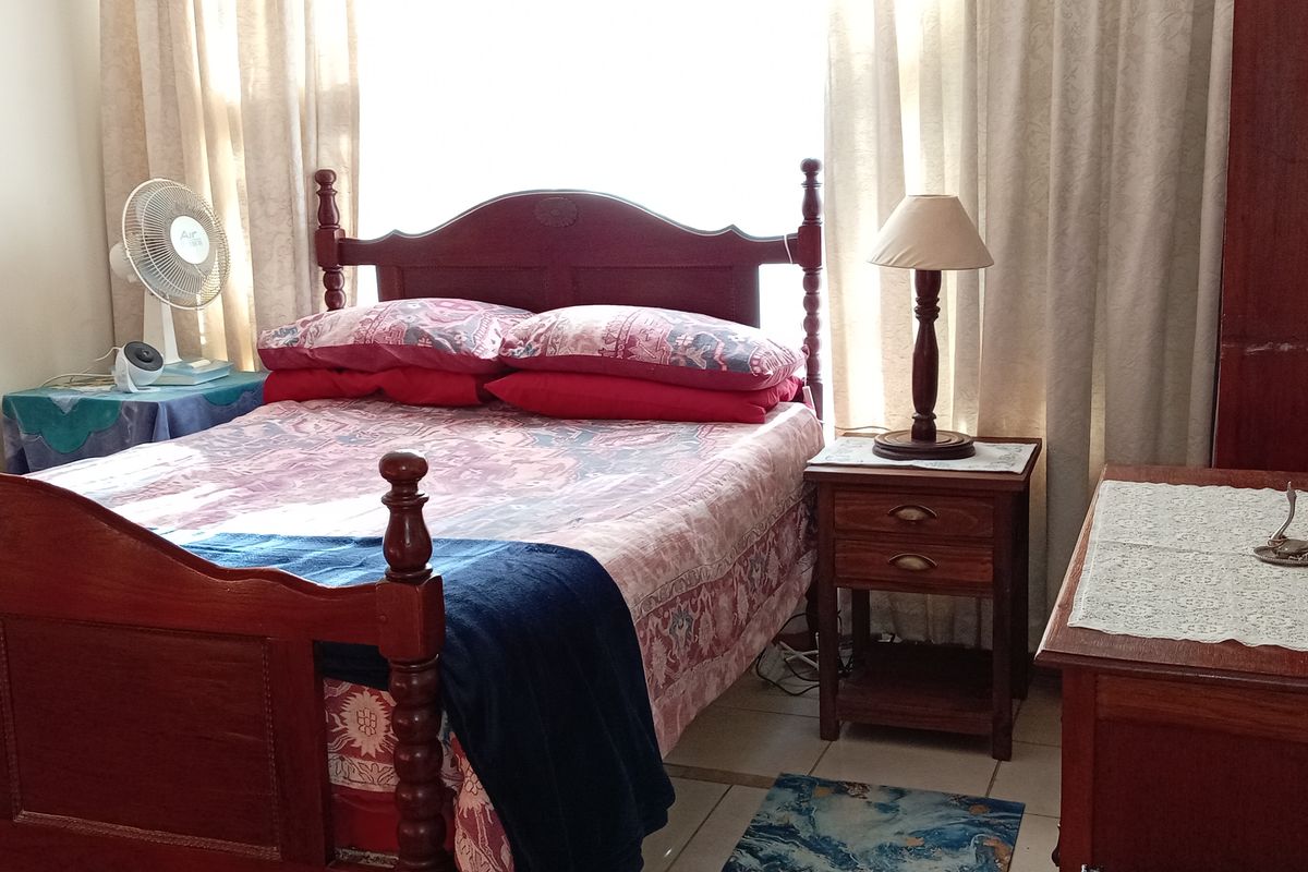 A functional bedroom featuring tiled flooring and neutral wall finishes, providing a comfortable and practical sleeping space.