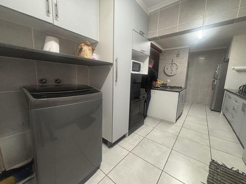 Functional kitchen featuring tiled flooring, stone countertops, built-in cabinetry, and integrated cooking appliances, providing a practical workspace for daily meal preparation.