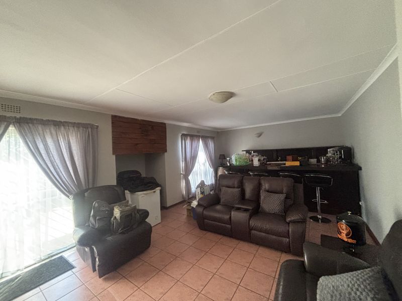 A spacious entertainment room featuring a built-in bar counter, tiled flooring, and sliding glass doors providing access to the outdoor area.