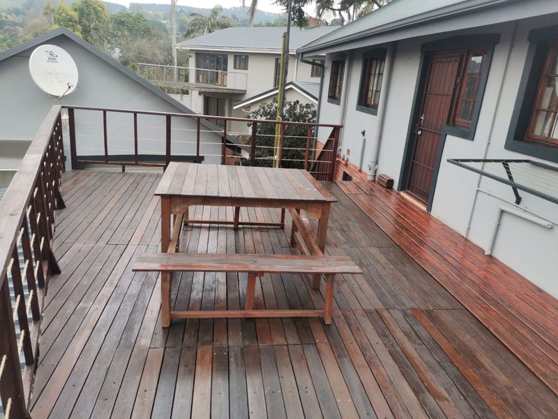An elevated timber deck balcony featuring a wooden balustrade and direct access to the building exterior.