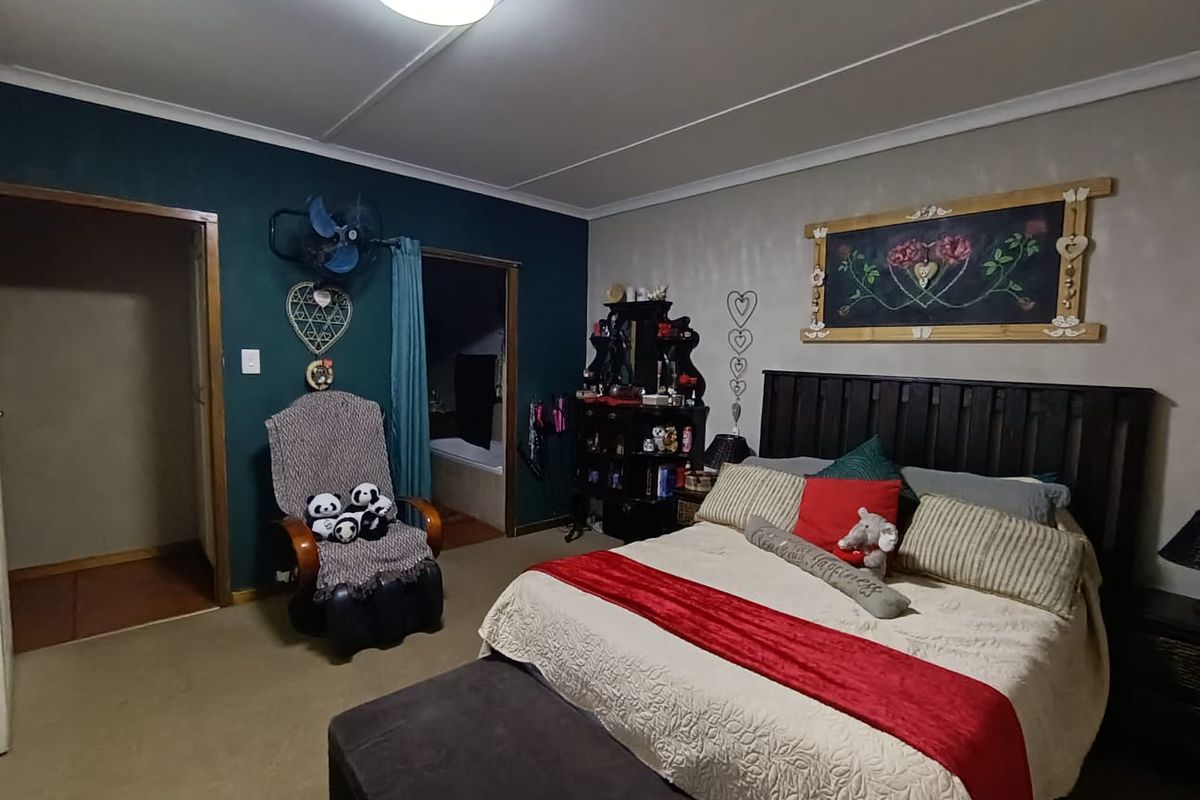 Spacious bedroom featuring carpeted flooring, coved ceilings, and an en-suite bathroom access point.