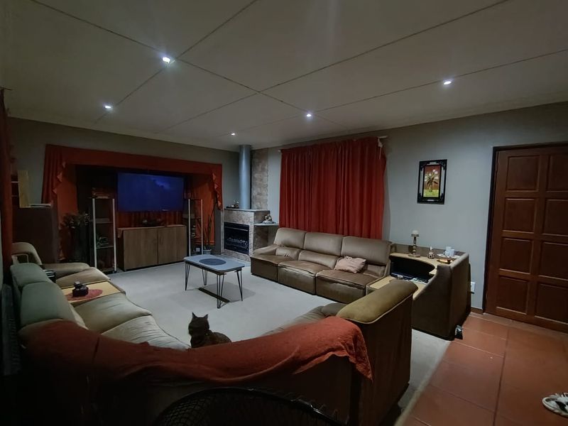 Spacious living room featuring a built-in fireplace, recessed ceiling lighting, and a combination of tiled and carpeted flooring.